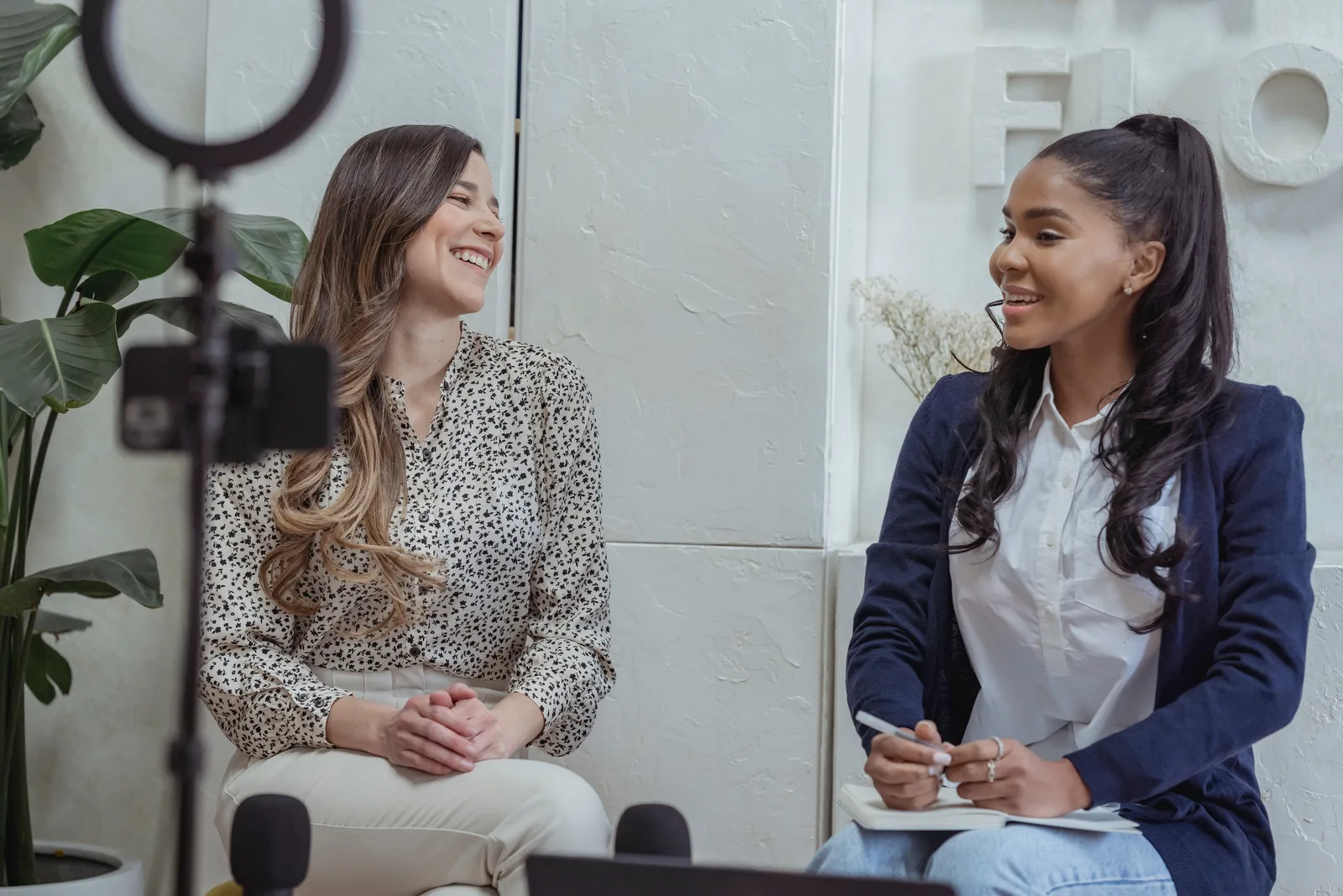 Two women engaged in a lively conversation in a professional interview setting.