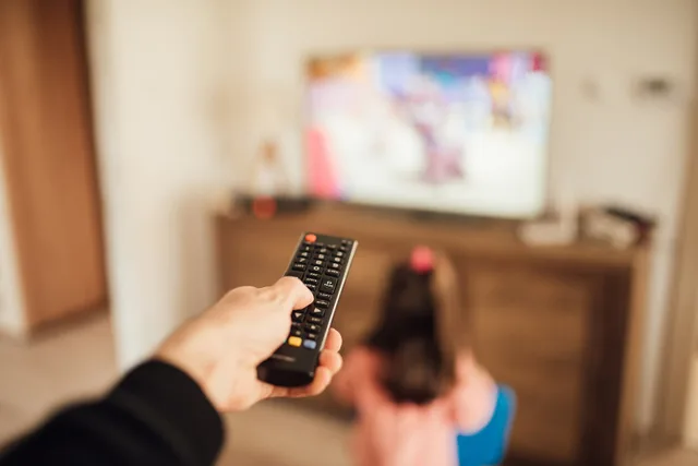 Parent using a remote control and young girl in front of a television in a blurry background. What connected TV advertising measurement mistakes mean for UK planners