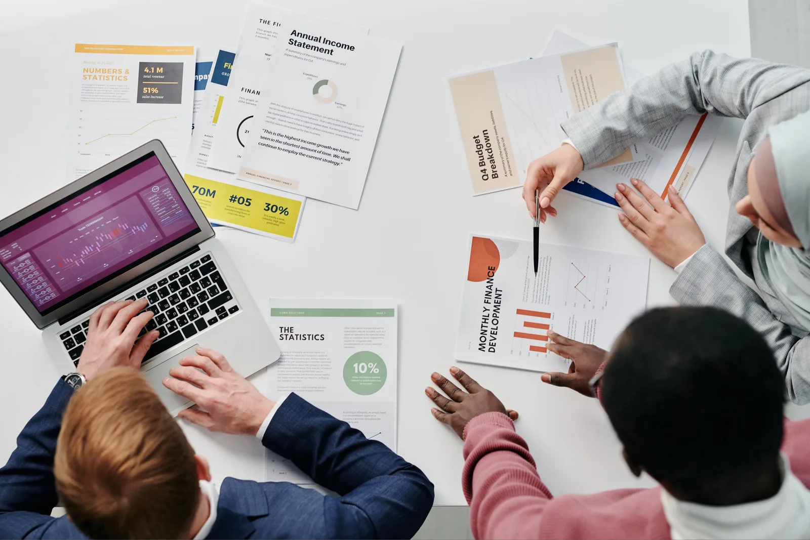 Business meeting with professionals discussing financial reports and graphs at a work desk.
