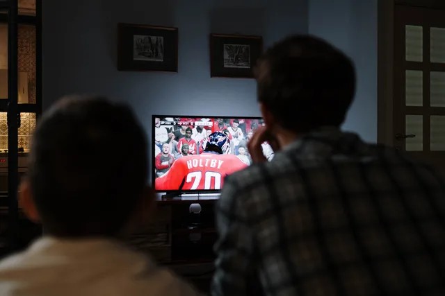 Father and son enjoying a hockey game together on TV from their living room. Planning connected TV advertising: a UK budget guide